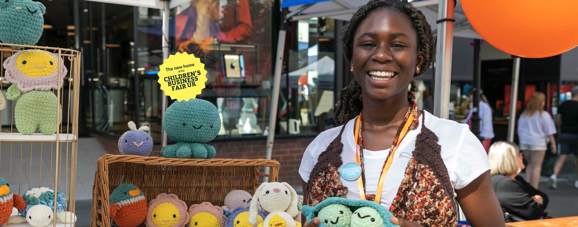 Smiling-young-entrepreneur-displays-her-crochet-at-the-Young-Business-Showcase_Badge